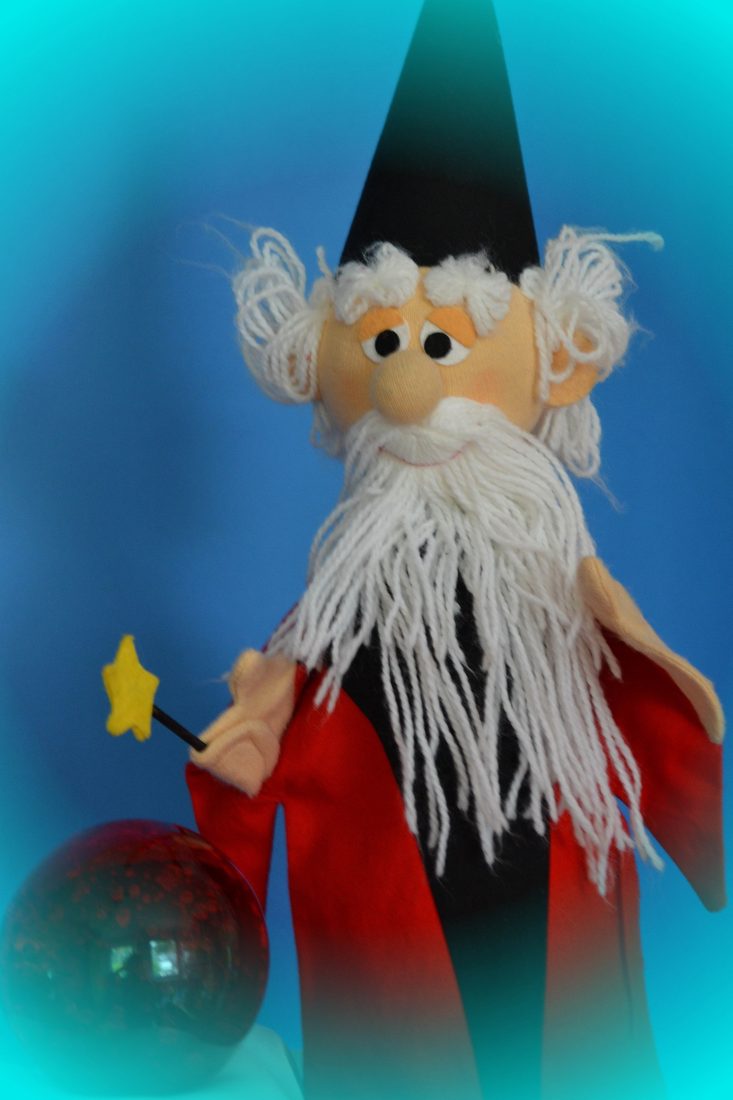 Zauberer-Puppe mit Zauberstab und leuchtender Kristallkugel.